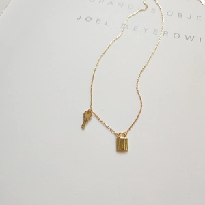Detail of a 925 sterling silver gold-plated necklace with padlock and key charms