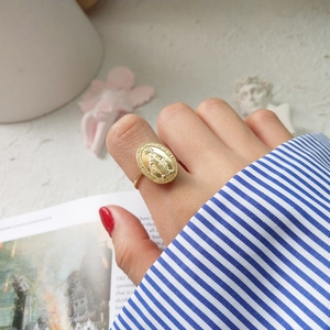 Macro detail of vintage gold oval Virgin Mary medallion ring worn on index finger