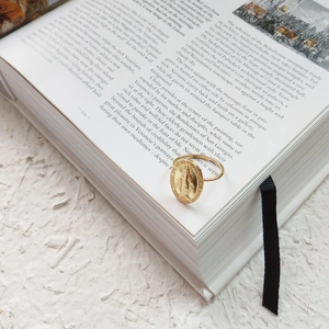 Detailed view of an oval vintage gold Virgin Mary signet ring on a classic art book