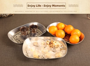 Detail of oval stainless steel trays with floral Home engraving on a rustic table