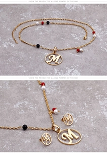 Details des goldenen Schmucksets mit Buchstaben M und bunten Perlen auf Marmor