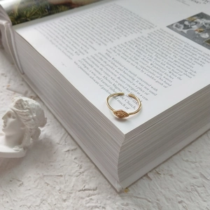 Detail of gold evil eye ring with radiant texture on open vintage book pages