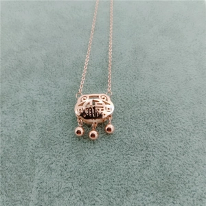 Detail of rose gold titanium steel longevity lock necklace with tassels on green velvet