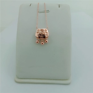 Macro shot of rose gold titanium lock pendant with lucky Fu character and beads