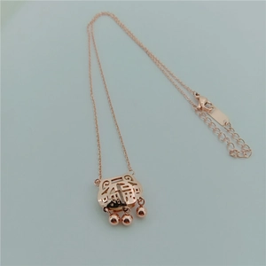 Macro detail of rose gold hollow Fu character lock pendant with three dangling beads