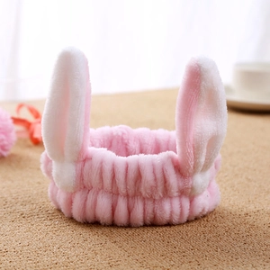 Detail shot of soft pink plush cat ear headband on a textured wooden background