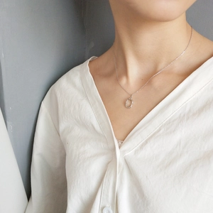 Close-up of minimalist 925 sterling silver irregular oval pendant on thin chain