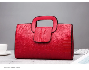 Detailed view of red crocodile-embossed handbag with a unique 3D crocodile head buckle