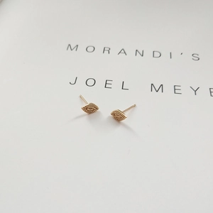 Detailed close-up of 925 sterling silver golden evil eye stud earrings on card