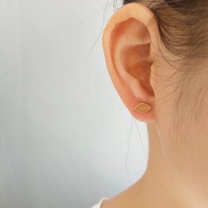 Close-up view of gold evil eye stud earring made of 925 sterling silver on model ear