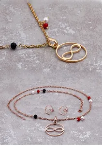 Detail von Infinity-Anhänger und Ohrringen mit roten, weißen und schwarzen Perlen