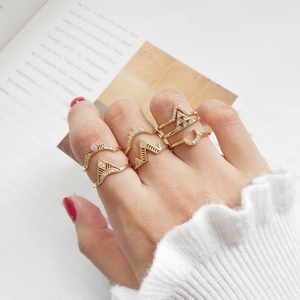 Close-up of gold geometric rings with rhinestones on a hand against book background