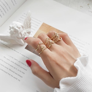 Close-up of elegant gold geometric rings set with zircon worn on fingers over a book