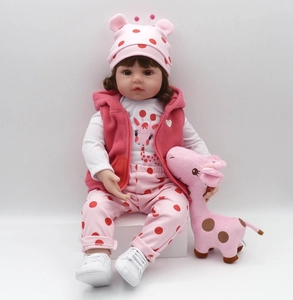 Detail of 47cm reborn doll in pink polka dot outfit with a giraffe plush toy