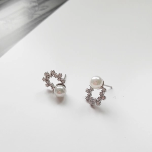 Detailed view of 925 silver stud earrings featuring zircon pavé and white round pearls