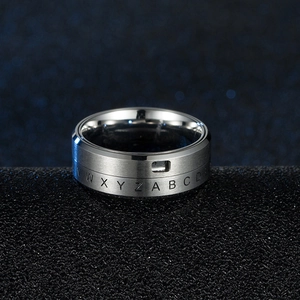 Close-up of rotatable titanium steel ring with engraved alphabet letters on a black surface
