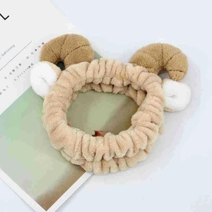 Macro detail of soft coral fleece headband with plush ram horns and cat ears for skincare