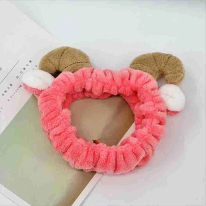 Detail of pink plush headband with cute brown sheep horns and white ears on magazine