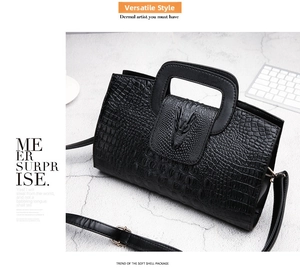 Close-up of black crocodile-embossed leather handbag with a unique metal dragon head clasp