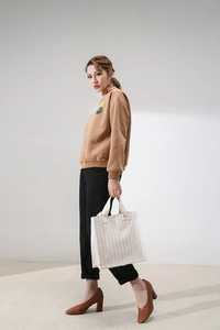 Minimalist beige striped canvas tote bag styled with casual brown sweatshirt and black trousers