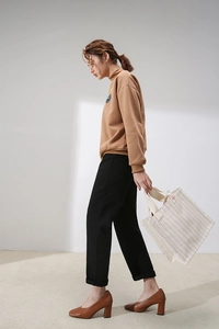 Detail shot of a model carrying a cream canvas tote with red stripes and casual outfit