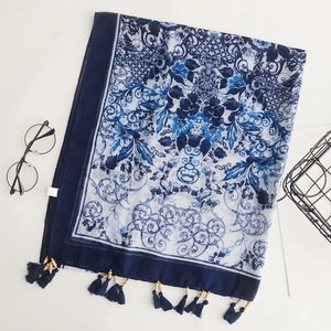 Detail of bohemian scarf featuring blue white print and decorative wooden bead tassels