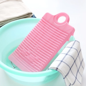 Pink mini plastic washboard with non-slip waves placed in a green basin for laundry