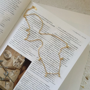 Detail of 925 silver gold beaded necklace resting on an open art book page
