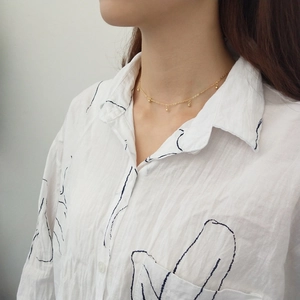 Close-up of minimalist 925 silver golden choker necklace with five small beads on a model