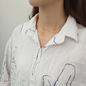 Detail of a 925 sterling silver gold beaded necklace worn on a collarbone for women