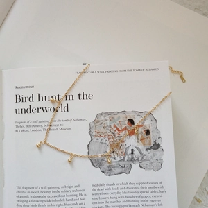 Close-up of a 925 sterling silver gold beaded necklace on a vintage art book background