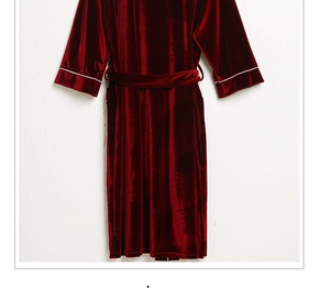 Detail of burgundy velvet robe featuring elegant white piping on sleeves and waist tie