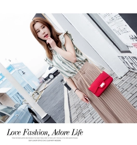 Detail of red V-quilted chain crossbody bag with golden metal lock and strap
