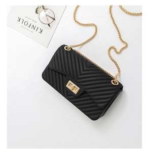 Flat lay of black V-quilted jelly crossbody bag with golden chain strap and Kinfolk magazine