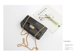 Chic black V-quilted chain bag with golden lock shown in a stylish flat lay set