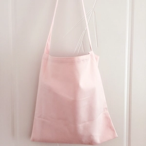 Detail of light pink canvas tote bag showing wide shoulder strap and fabric texture