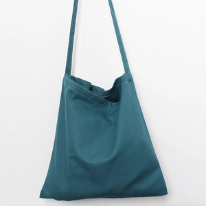 Detail of reinforced stitching and dark green canvas texture on a minimalist tote bag