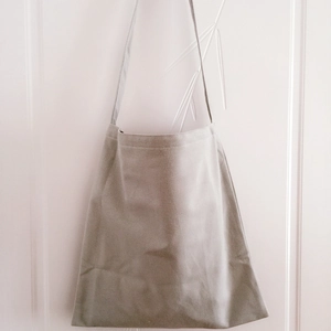 Minimalist light gray canvas tote bag hanging on a simple white door hook detail