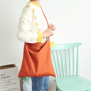 Close-up of vibrant orange canvas crossbody bag showing thick fabric texture and wide strap