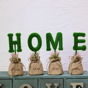 Detail view of four HOME green flocking artificial letter plants in burlap love bags