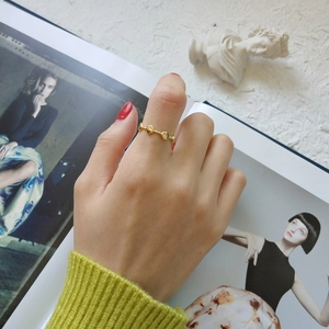 Detailed close-up of a minimalist gold beaded ring worn on hand with a fashion background