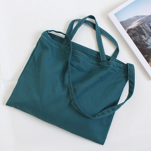 Detailed view of dark green canvas tote bag with white stitching and shoulder strap