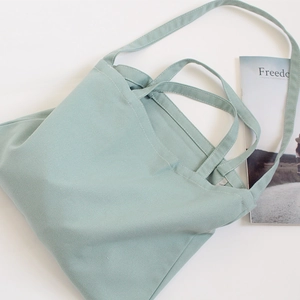 Detail of mint green canvas tote bag showing dual handle stitching and soft texture