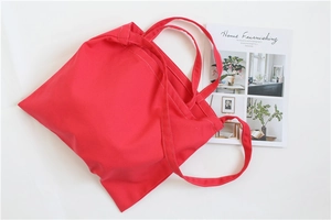 Flat lay view of a red canvas tote bag with magazine prop on white background
