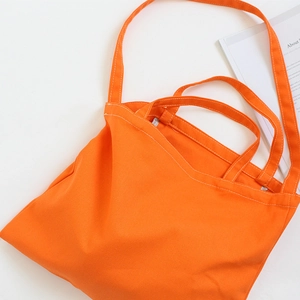 Detail view of bright orange canvas tote bag with dual straps and reinforced stitching