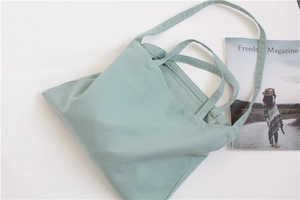 Flat lay of a mint green canvas tote bag with dual handles and long shoulder strap