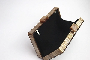 Detail view of the open marble acrylic clutch bag showing black interior lining and clasp