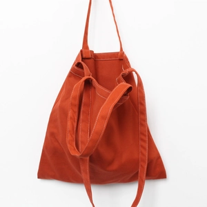 Detail of orange canvas tote bag with contrast white stitching and double strap design