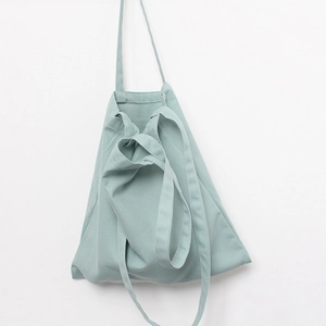 Detail view of sage green canvas tote bag featuring dual shoulder and hand carry straps