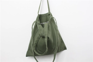 Detail view of army green canvas tote bag with long straps on minimalist background